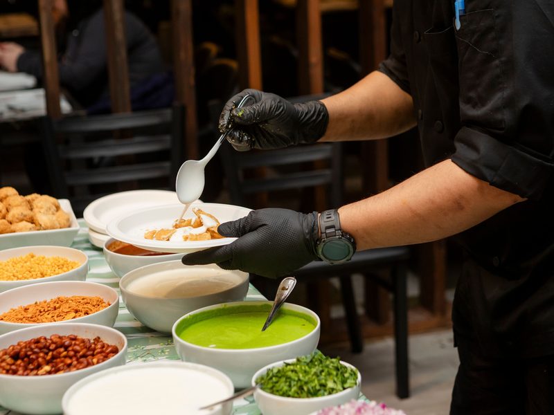Chef assembling chaat to order at a live street-food counter